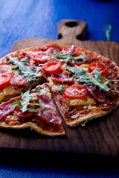 Ev yapımı pizza salam, domates, roka ahşap Pano mavi zemin üzerine.