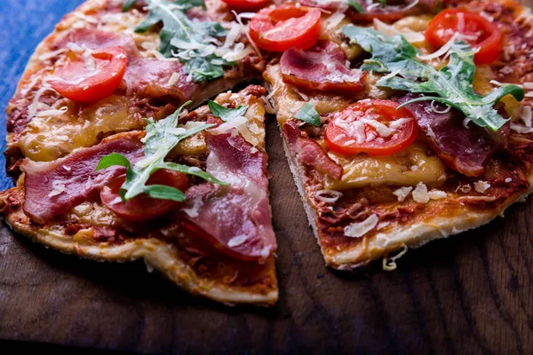 Ev yapımı pizza salam, domates, roka ahşap Pano mavi zemin üzerine.