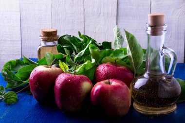 Elma sirkesi. Mavi arka plan üzerinde üç cam şişe. Kırmızı elma