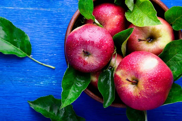 Manzanas rojas en tazón marrón sobre fondo azul de madera. Vista superior. Copiar espacio — Foto de Stock