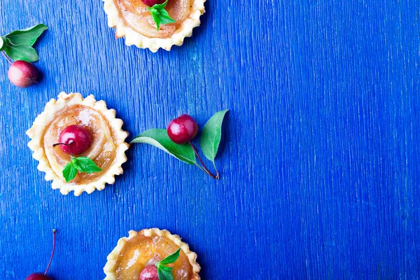 Apple sockerkulör lite tårtor på blå rustika bakgrund. Franska tatin med paradise apple. Ovanifrån. Ram. Kopiera utrymme. — Stockfoto