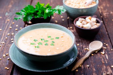 Kahverengi ahşap zemin üzerine yeşil kase bezelye çorbası. Kuru sarı bezelye. Vegan gıda.