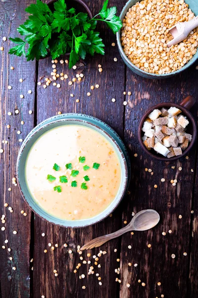 Soupe de pois dans un bol vert sur fond de bois brun. Vue de dessus. Pois jaune sec. Alimentation végétalienne . — Photo