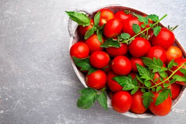 Gri arka plan üzerinde gri sepet içinde kırmızı domates. Üstten Görünüm. Uzay kopyalayın. Hasat. Domates dolu kutu.