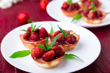 Kırmızı zemin üzerine beyaz plakalar üzerinde çilek tartı.