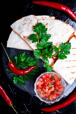 Mexican quesadilla siyah arduvaz taş plaka üzerinde salsa sos ile. Biber biber. Üstten Görünüm.