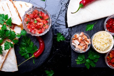Mexican quesadilla ve siyah arduvaz taş plaka üzerinde salsa malzemelerle