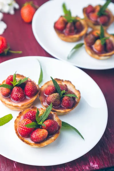 Tartaleta de fresa sobre platos blancos sobre fondo rojo. Fotografía tonal. Flor decorada . — Foto de Stock