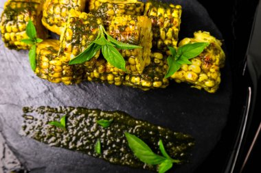 Izgarada Mısır siyah arduvaz plaka üzerinde pesto sos ile. Üstten Görünüm. Vegan gıda.