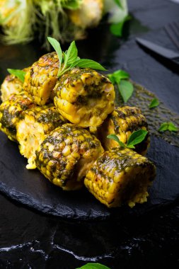 Izgarada Mısır siyah arduvaz plaka üzerinde pesto sos ile. Yakın çekim. Vegan gıda.