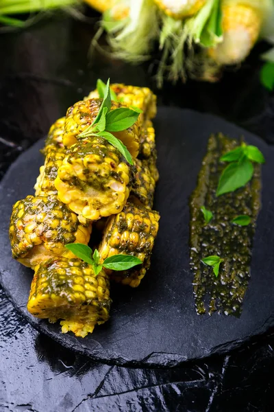 Izgarada Mısır siyah arduvaz plaka üzerinde pesto sos ile. Yakın çekim. Vegan gıda.