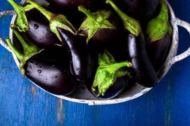 Taze patlıcan mavi ahşap masa üzerinde gri sepet içinde. Rustik arka plan. Üstten Görünüm. Uzay kopyalayın. Vegan sebze.