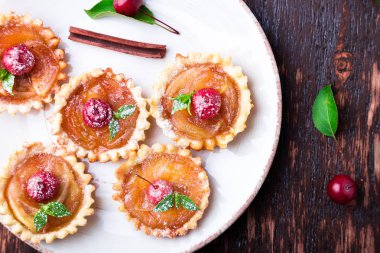 Karamel küçük tarts beyaz plaka ve kahverengi rustik zemin üzerinde Apple. Cennet elması ile Fransız tatin. Üstten Görünüm.