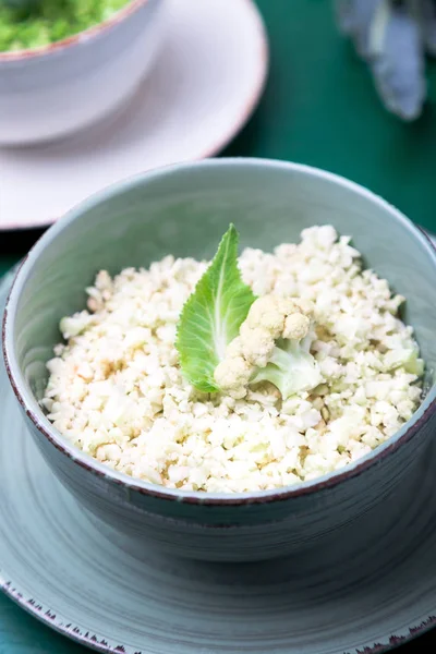 Рис из цветной капусты и брокколи в миске на зеленом фоне. Измельченные . — стоковое фото