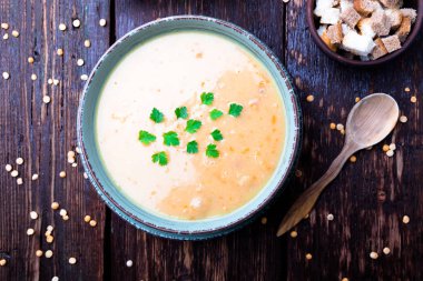 Kahverengi ahşap zemin üzerine yeşil kase bezelye çorbası. Üstten Görünüm. Kuru sarı bezelye. Vegan gıda.