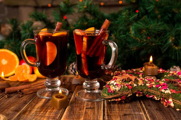 Christmas mulled wine with fruits and spices on wooden table. Xmas decorations in background. Two glasses. Winter warming drink with recipe ingredients around. — Stock Photo, Image