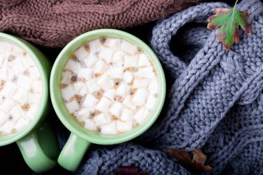 İki fincan kahve ya da sıcak çikolata hatmi üç yakınındaki gri, siyah ve kahverengi süveter örme veya battaniye örme. Sonbahar kavramı. Noel. Üstten Görünüm. Evde sıcak.