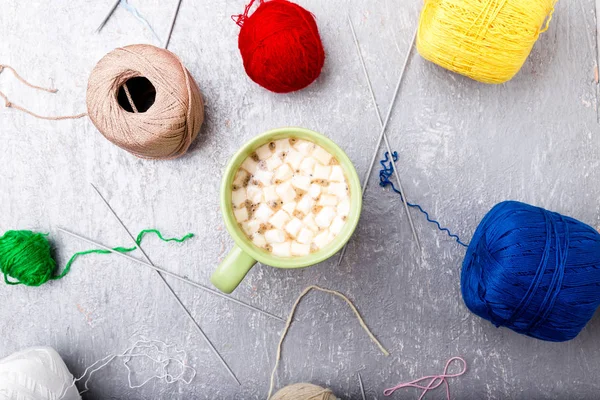 Multicolor knitting ball and needles around green cup of coffee  on grey background. Top view. Copy space. Knitting yarn. — Stock Photo, Image