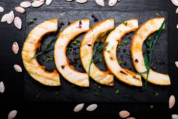 Siyah arka plan üzerine siyah arduvaz plaka üzerinde ızgara balkabağı. Üstten Görünüm.