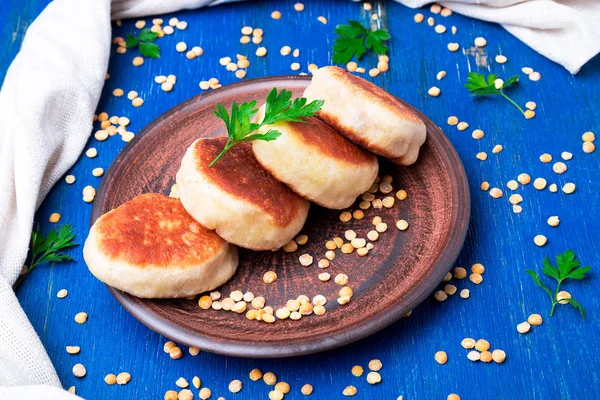 Bezelye patty mavi ahşap arka plan üzerinde kahverengi plaka kavrulmuş. Yakın çekim.