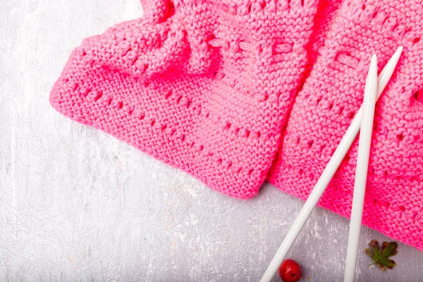 Pink scarf near knitting needles on grey background. Top view. Copy space. — Stock Photo, Image