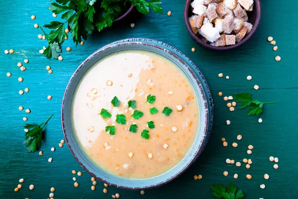 Yeşil ahşap zemin üzerine yeşil kase bezelye çorbası. Üstten Görünüm. Kuru sarı bezelye. Vegan gıda.