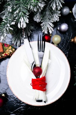 Noel tablo yer ayarını. Tatil arka plan. Beyaz tabak, bıçak ve çatal ile Noel süslemeleri siyah masada. Üstten Görünüm.
