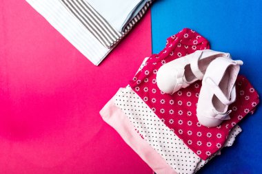 Tekne ayakkabı ile mavi ve pembe gömlek üzerine minimalist pembe ve mavi zemin üzerine katlanmış. Yeni doğan erkek ve kız çocuk için bebek bezi. Bebek Giyim yığını. Çocuk kıyafeti. Üstten Görünüm.