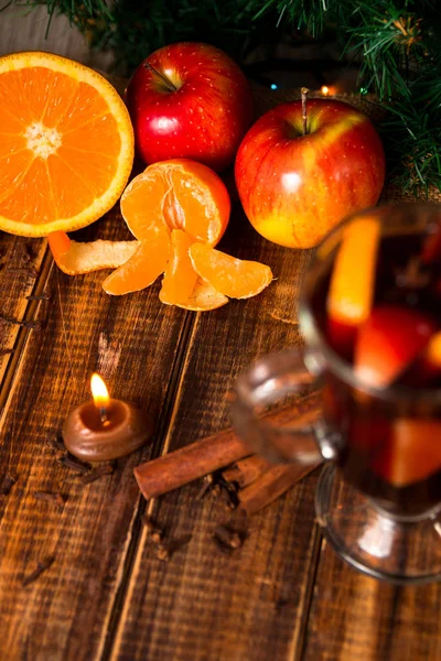 Gyertya, narancssárga gyümölcs, alma, fahéj rúd, forralt bor, fa háttér közelében. Karácsonyi dekoráció. Új év — Stock Fotó