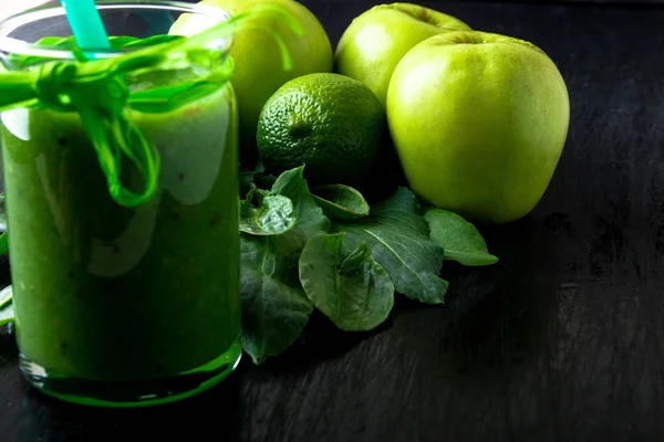 Smoothie vert près des ingrédients pour elle sur fond de bois noir. Pomme, citron vert, épinards. Désintoxication. Une boisson saine. Aliments clairs . — Photo