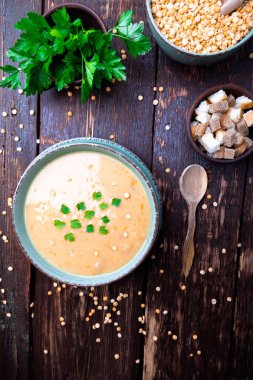 Kahverengi ahşap zemin üzerine yeşil kase bezelye çorbası. Üstten Görünüm. Kuru sarı bezelye. Vegan gıda.