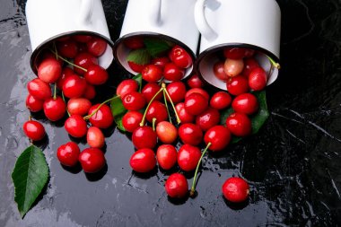 Dağınık kiraz emaye bardak dan. Kiraz demir Kupası siyah arka plan üzerine. Sağlıklı, yaz meyve. Kiraz. Üç. Üstten Görünüm.
