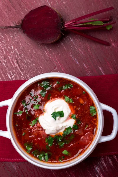 Традиційний український борщ. Російський вегетаріанські червоний суп в білі чаші на червоному тлі дерев'яні. Вид зверху. Борщ, Борщ з буряка. — стокове фото