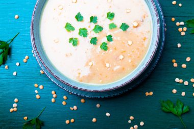 Yeşil ahşap zemin üzerine yeşil kase bezelye çorbası. Üstten Görünüm. Kuru sarı bezelye. Vegan gıda.