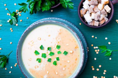 Yeşil ahşap zemin üzerine yeşil kase bezelye çorbası. Üstten Görünüm. Kuru sarı bezelye. Vegan gıda.