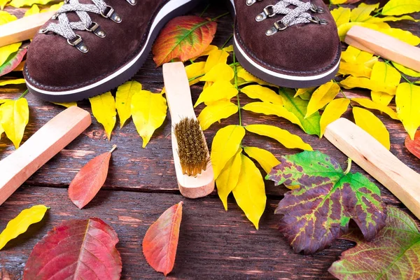 Botas de gamuza marrón sobre fondo de madera con hojas. Cepillos de gamuza para zapatos. Zapatos de otoño o invierno . —  Fotos de Stock