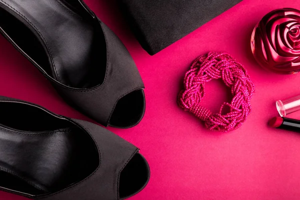 Набір модних аксесуарів для леді. Чорно-рожевий. Мінімум. Чорне взуття, браслет, парфуми, помада та сумка на рожевому тлі. Плоский прошарок . — стокове фото