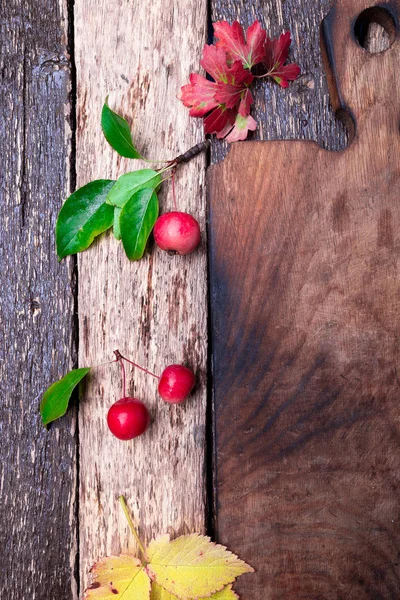 Hojas y pequeña manzana alrededor de la tabla de cortar vacía sobre fondo rústico de madera. Vista superior. Una trampa. Copiar espacio. Día de Acción de Gracias. Puesta plana . —  Fotos de Stock