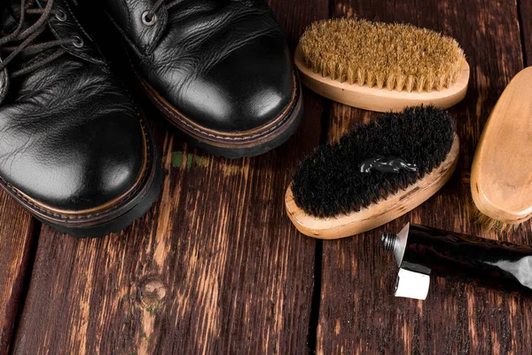 Parlatma donanımları, fırça ve Lehçe krem ile ahşap arka plan üzerinde siyah çizmeler. 