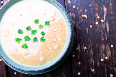 Kahverengi ahşap zemin üzerine yeşil kase bezelye çorbası. Üstten Görünüm. Kuru sarı bezelye. Vegan gıda.