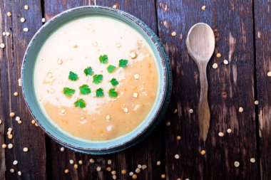 Kahverengi ahşap zemin üzerine yeşil kase bezelye çorbası. Üstten Görünüm. Kuru sarı bezelye. Vegan gıda.