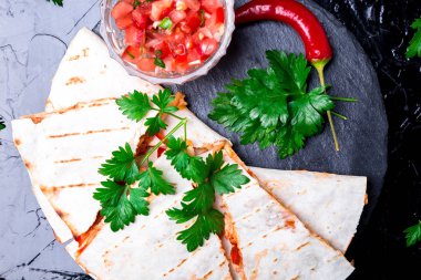 Mexican quesadilla siyah arduvaz taş plaka üzerinde salsa sos ile. Biber biber. Üstten Görünüm.