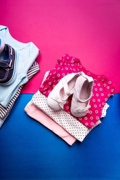 Bodysuit dobrado azul e rosa com sapatos de barco sobre ele em fundo minimalista rosa e azul. fralda para menino e menina recém-nascidos. Pilha de roupas infantis. Roupa de criança. Vista superior . — Fotografia de Stock