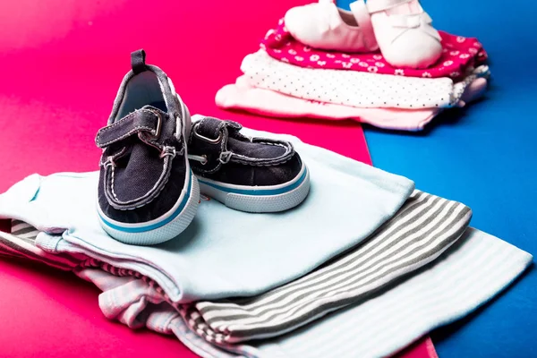 Carrocería plegada azul y rosa con zapatos de barco sobre fondo minimalista rosa y azul. pañal para niños y niñas recién nacidos. Montón de ropa infantil. Equipo de niño —  Fotos de Stock