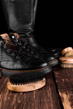 Parlatma donanımları, fırça ve Lehçe krem ile ahşap arka plan üzerinde siyah çizmeler. 