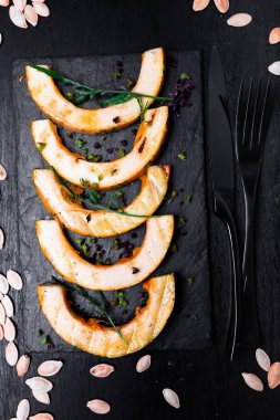 Siyah arka plan üzerine siyah arduvaz plaka üzerinde ızgara balkabağı. Üstten Görünüm.