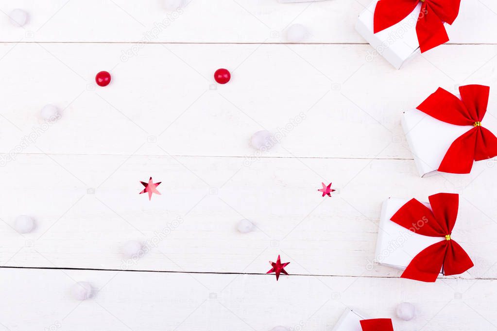 Christmas gifts, white little boxes with red bow  and candies on white wooden background. Flat lay. Merry Christmas.
