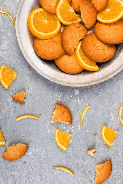 Pliki cookie i pomarańczowe owoce cytrusowe na metalowej tabliczce na szarym tle. Leżał z płaskim — Zdjęcie stockowe