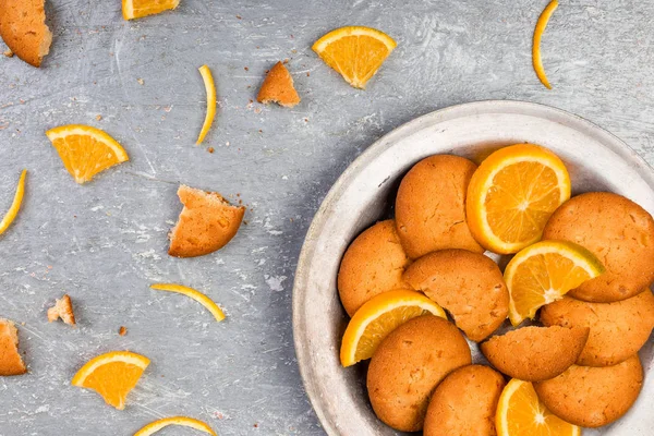 Pliki cookie i pomarańczowe owoce cytrusowe na metalowej tabliczce na szarym tle. Leżał z płaskim — Zdjęcie stockowe