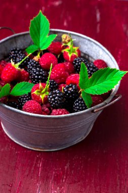 BlackBerry ve kırmızı ahşap zemin üzerinde metal bir kabın içinde ahududu